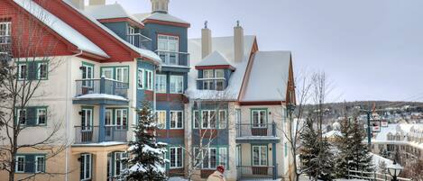 A multi-story building with balconies and a ski slope.