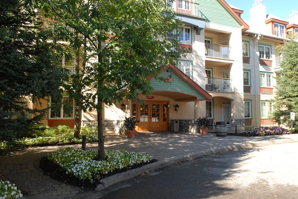 Ein mehrstöckiges Hotel mit einer Gründachfläche, einem zentralen Eingang mit rotem Markisenvorbau und Balkonen in den oberen Etagen.