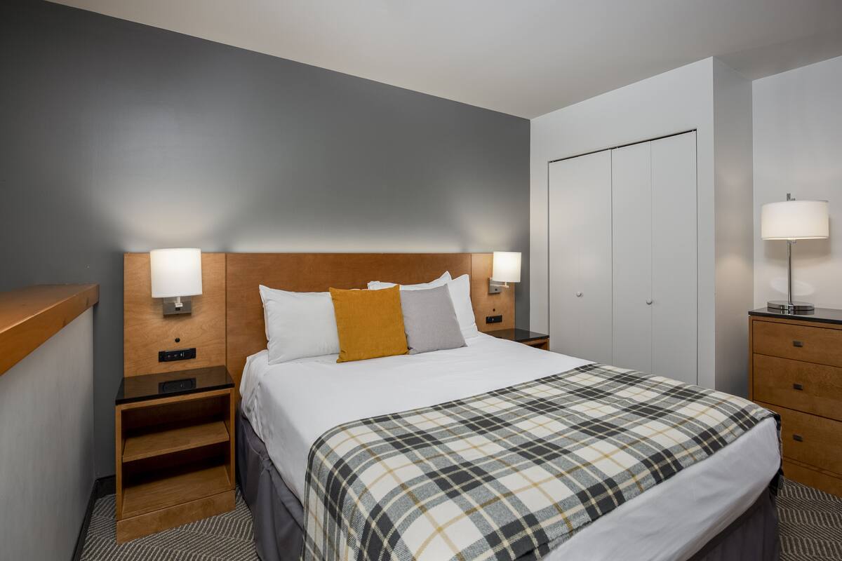 Ein Hotelzimmer mit Bett, Nachttischen, einem Schrank und einer Lampe.