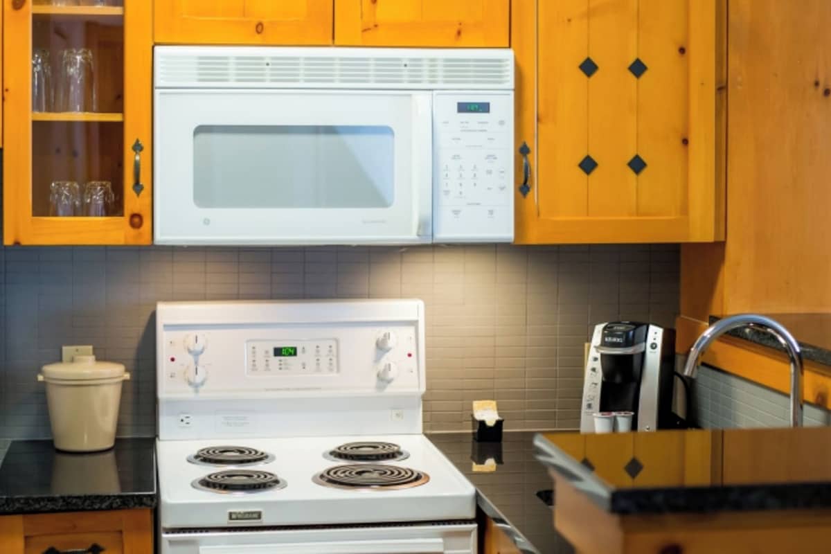 A kitchen with wooden cabinets, a microwave, a stove, and a refrigerator.