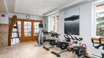A gym with exercise equipment, a clock, and a scenic window view.
