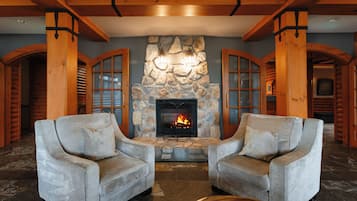 A cozy interior with a stone fireplace, two armchairs, and wooden beams.