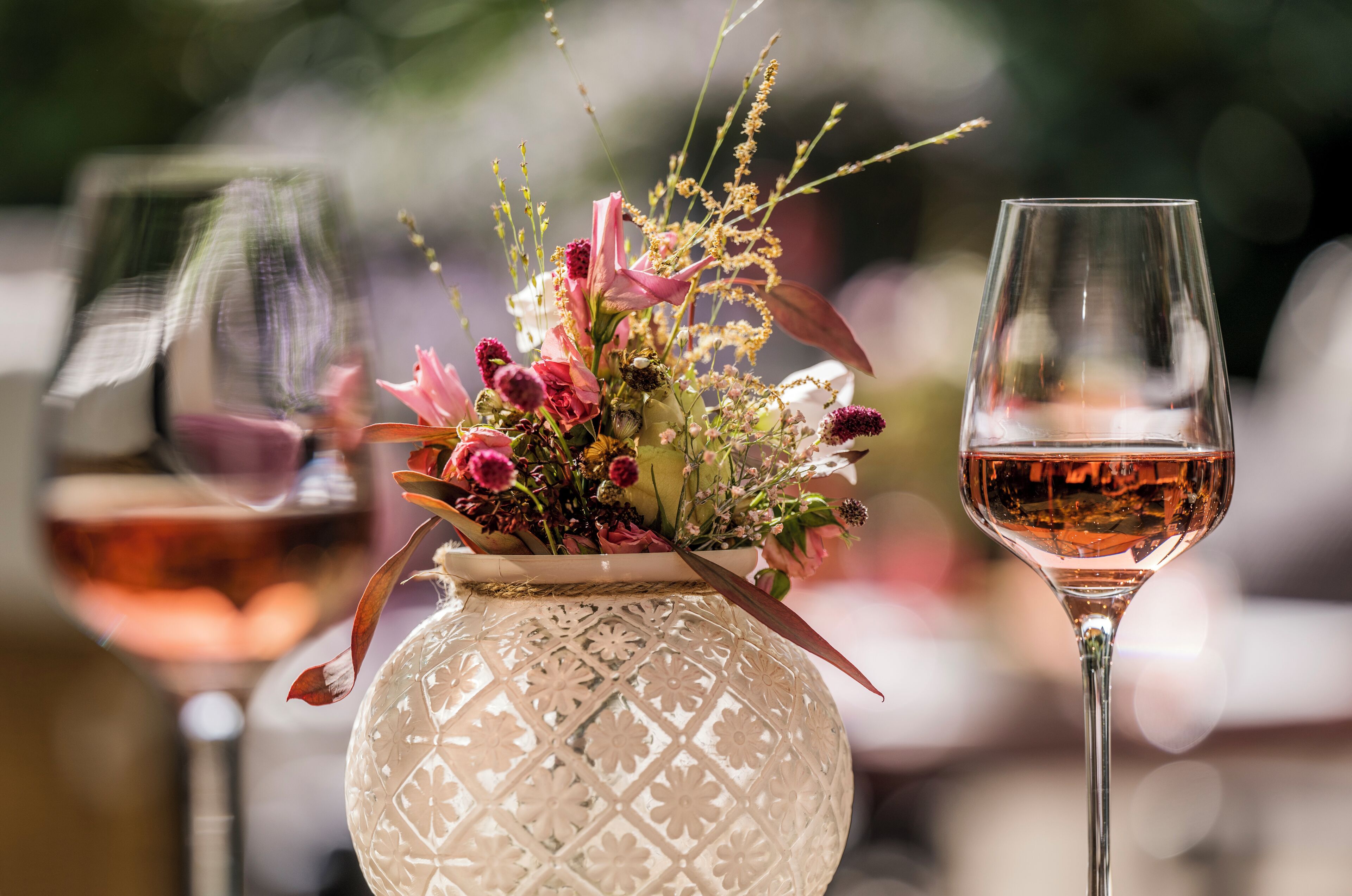 A table with a decorative vase and a wine glass.