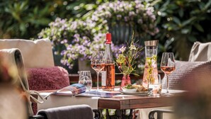 Mesa de comedor dispuesta con copas de vino, botellas y un jarrón con flores.