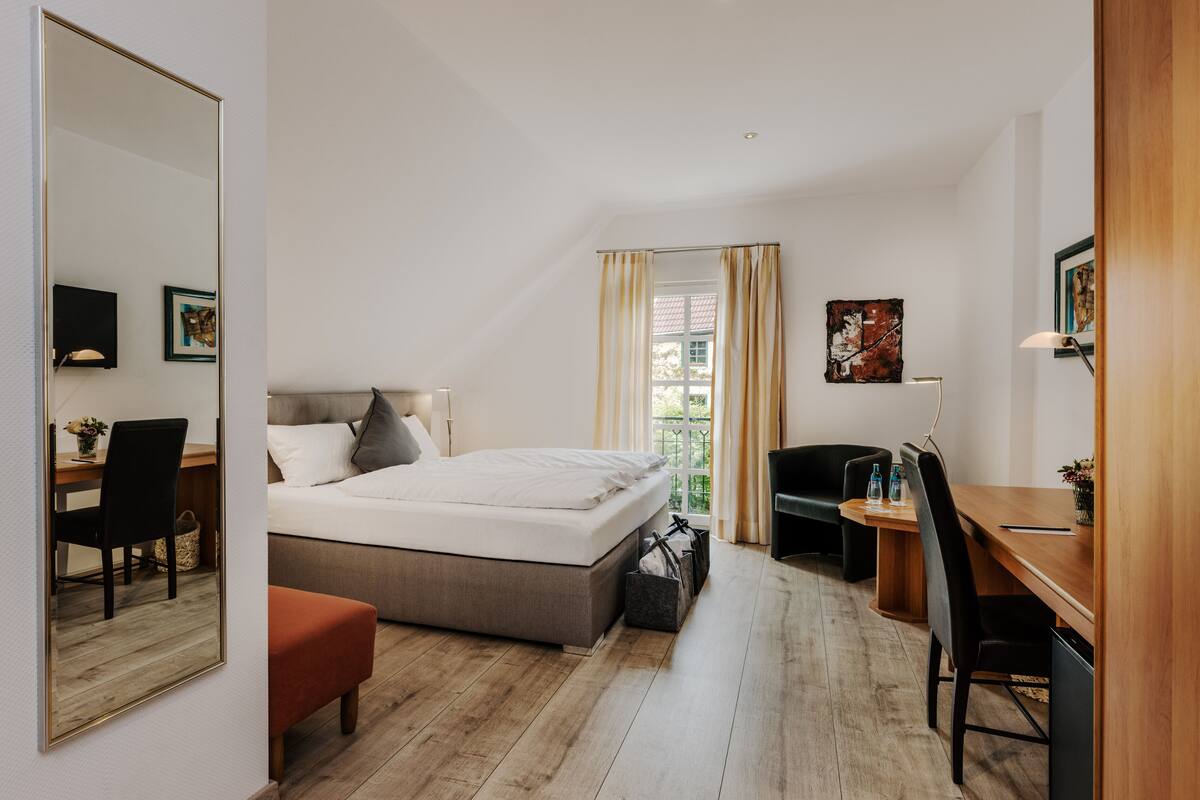 A modern bedroom with a large bed, a desk, a chair, and a small table.