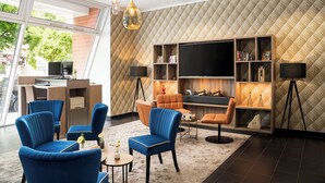 Una sala de estar moderna con sillones azul y naranja, un televisor de pantalla plana y una estantería.