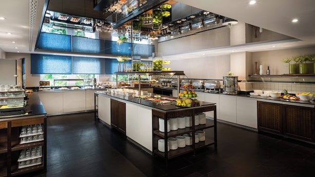 Una cocina moderna con una isla central, varias estaciones de servicio y una gran variedad de alimentos a la vista.