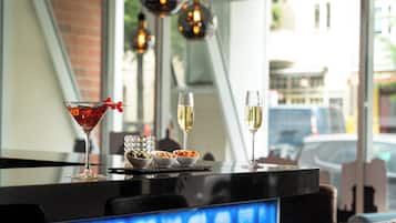 Eine Bar mit einem roten Cocktailglas, zwei Weingenüssen und Schalen mit Nüssen und Trockenfrüchten.