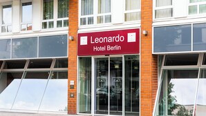 Un edificio de hotel con un llamativo letrero rojo que dice 'Leonardo Hotel Berlin' y grandes ventanales.