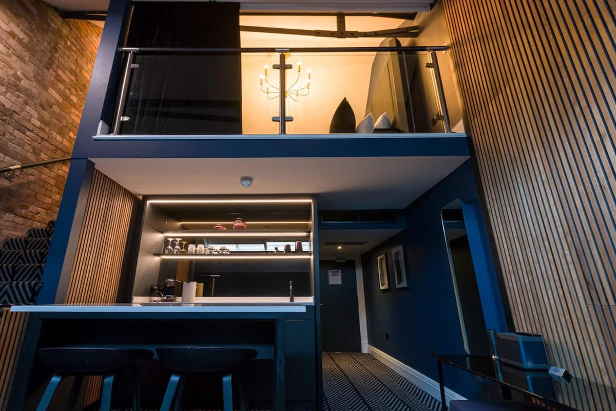 A modern kitchen with a bar area, a staircase, and a view of the city.