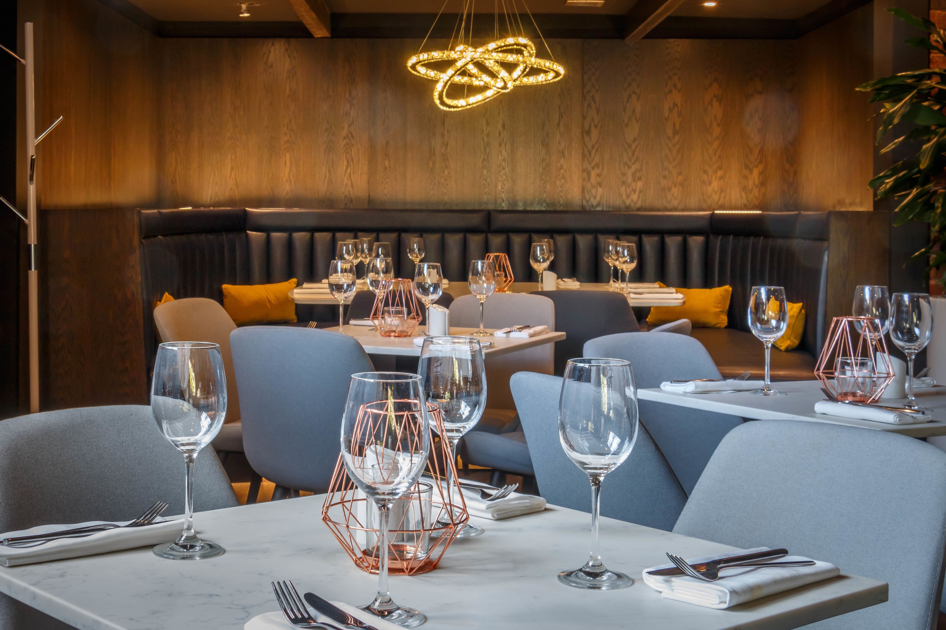 Ein Restaurant mit modernem Ambiente, das eine Holzwand, eine Neonleuchte und eine Sitzgelegenheit mit Tischen und Stühlen zeigt.