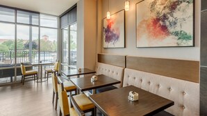 Un restaurant moderne doté de grandes fenêtres, de tables en bois et de banquettes confortables.