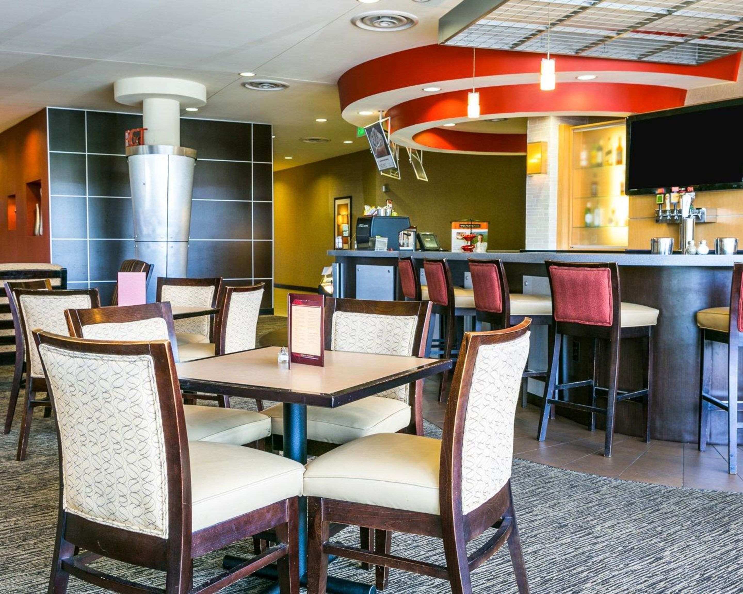 A hotel lobby with a bar area, seating arrangements, and a reception desk.