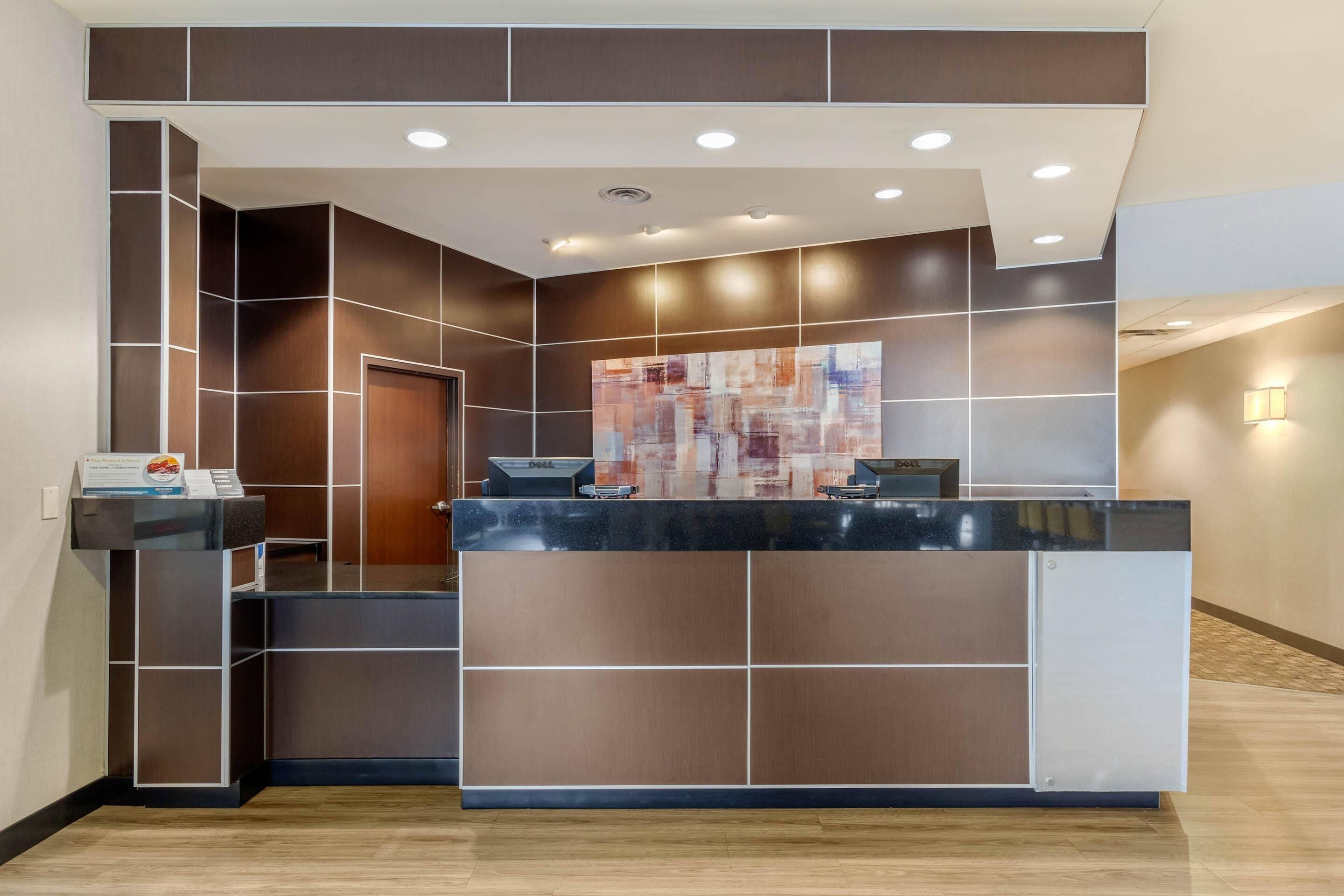 A reception desk with a modern design, a large abstract painting, and a door to the left.