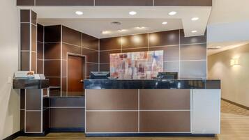 A reception desk with a modern design, a large abstract painting, and a door to the left.