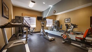 Une salle de sport équipée de divers appareils d’exercice, notamment des tapis de course et des vélos d ’appartement, et dotée d’un grand miroir qui reflète l’espace.