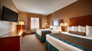 Une chambre d’hôtel avec deux lits, un bureau, un téléviseur à écran plat et une fenêtre avec des rideaux.