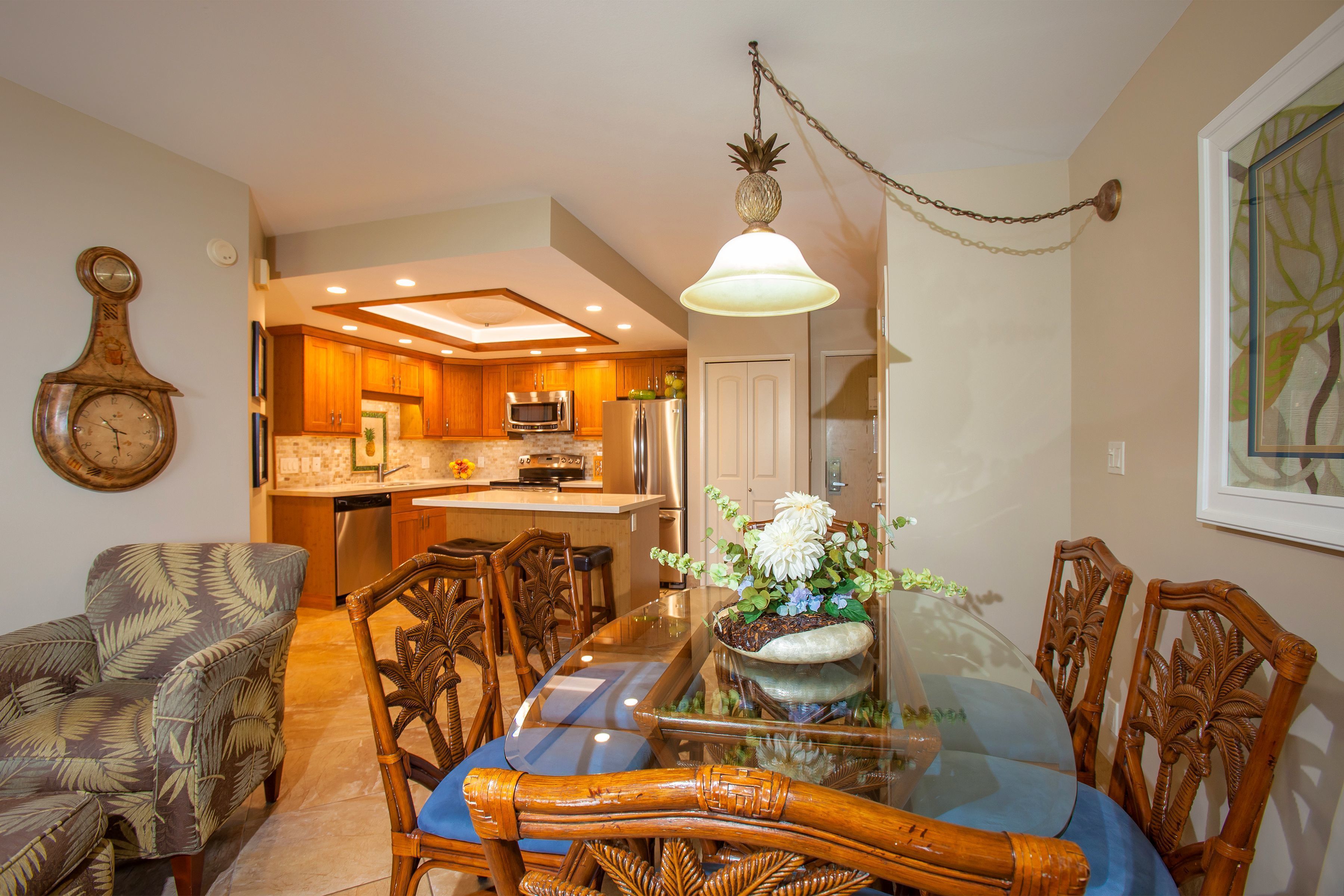 A dining area with a glass table, wooden chairs, and a hanging light fixture.