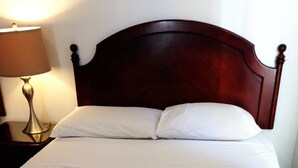 Una cama bien hecha con sábanas blancas y cabecera de madera.