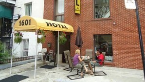 Un hotel con toldo amarillo que dice "1601 HOTEL" y mobiliario exterior.