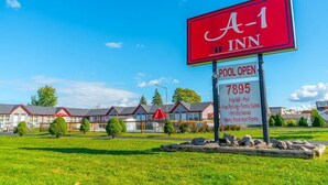 Un gran letrero del A-1 Inn con servicios listados, que incluyen WiFi gratuito, piscina, estacionamiento, suites familiares, casas de vacaciones y habitaciones recién renovadas.