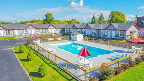 Un hotel con piscina, mobiliario exterior y un área cercada.