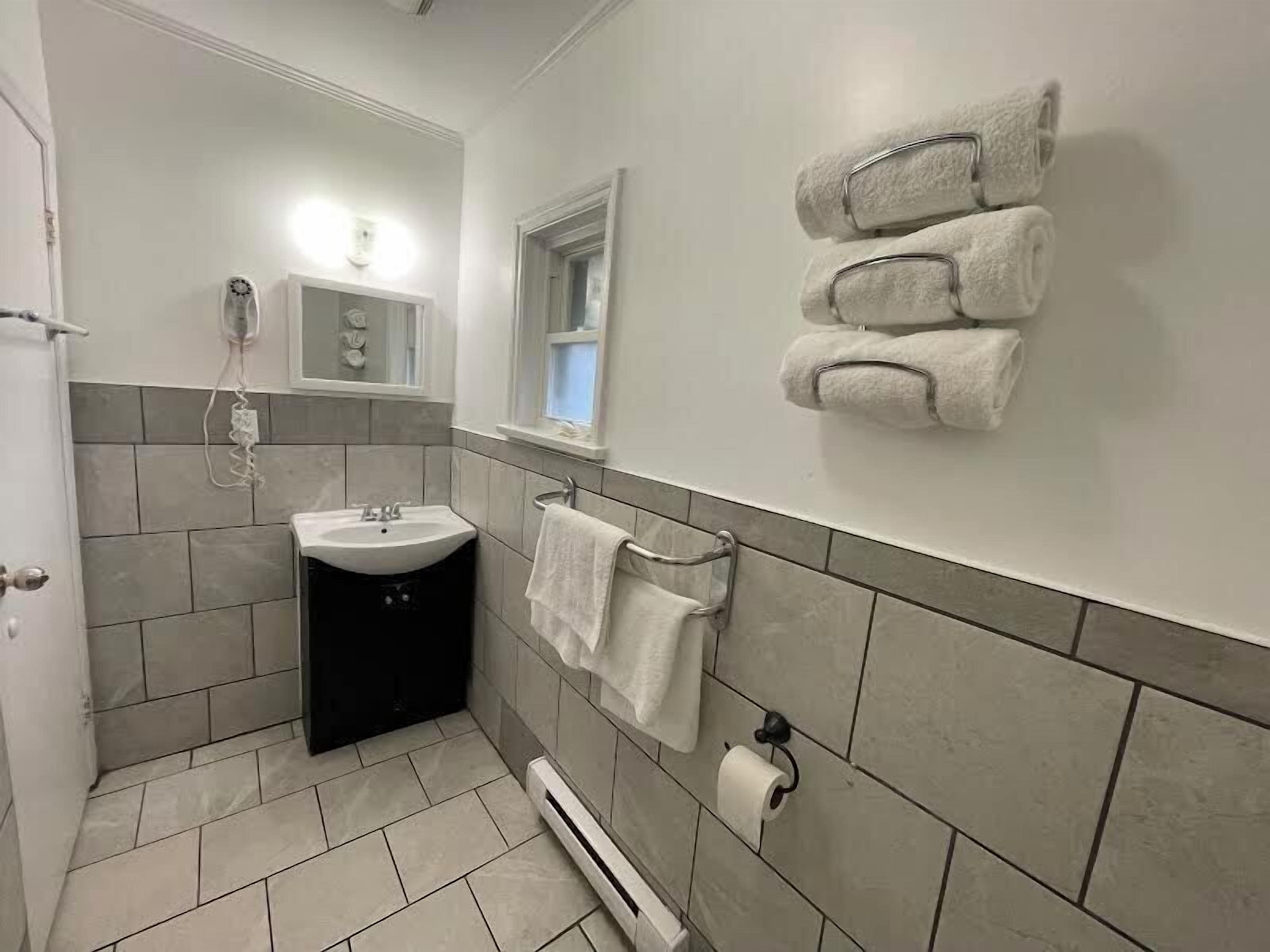 Ein Badezimmer mit Waschbecken, Handtuchhalter und Toilettenpapierhalter.