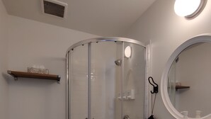 Un baño con ducha de vidrio, inodoro, lavabo y espejo.