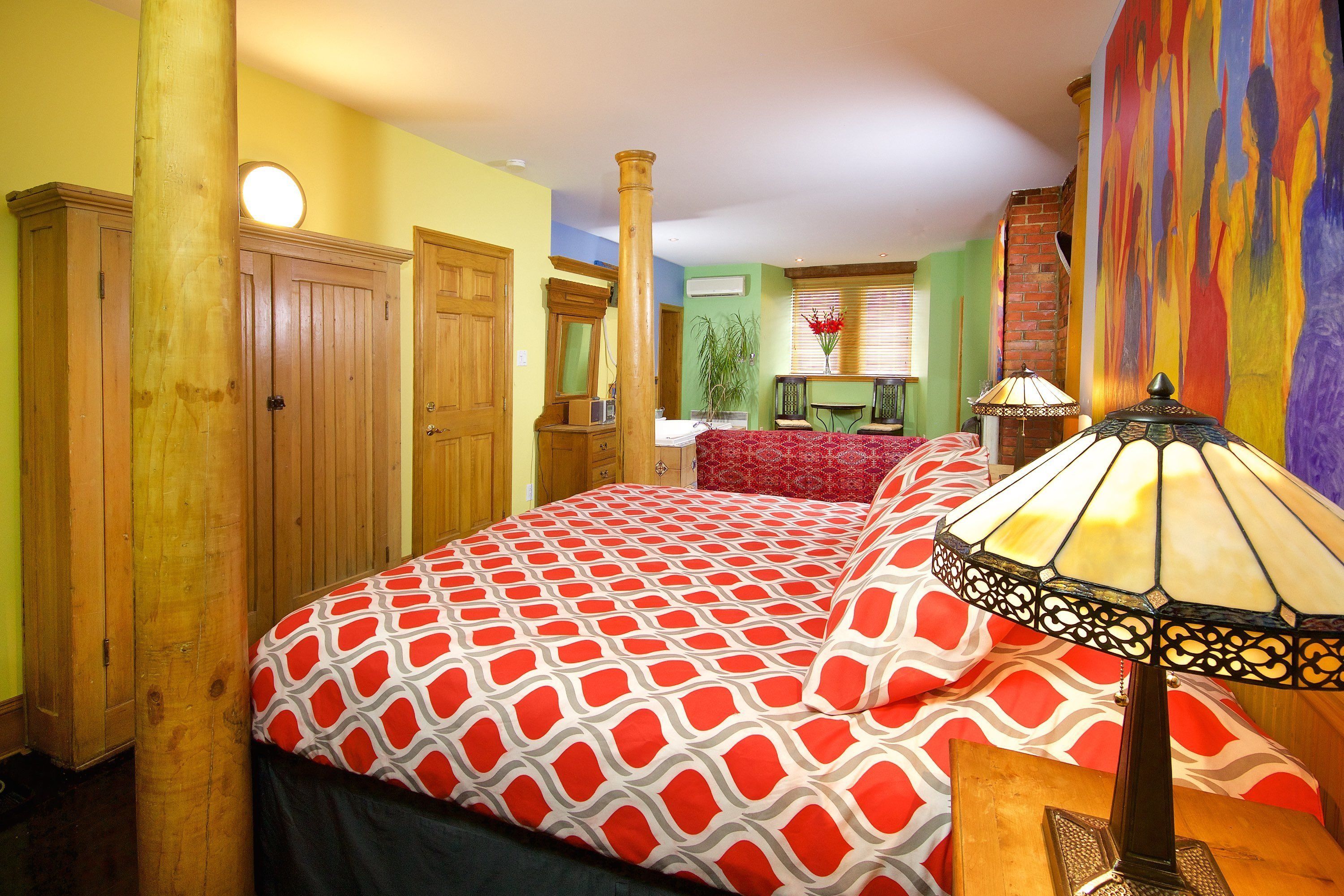 Een slaapkamer met een groot bed, een houten garderobe en een nachtkastje met een lamp.