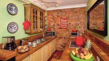 Eine Küche mit Backsteinwand, Holzschränken, einer Mikrowelle, einem Toaster und einer Obstschale.