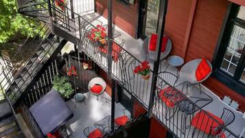 A multi-level outdoor terrace with red and white furniture, a staircase, and potted plants.