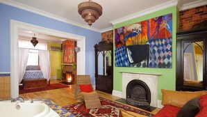 Una habitación con una bañera grande, una chimenea y un cuadro abstracto y colorido en la pared.