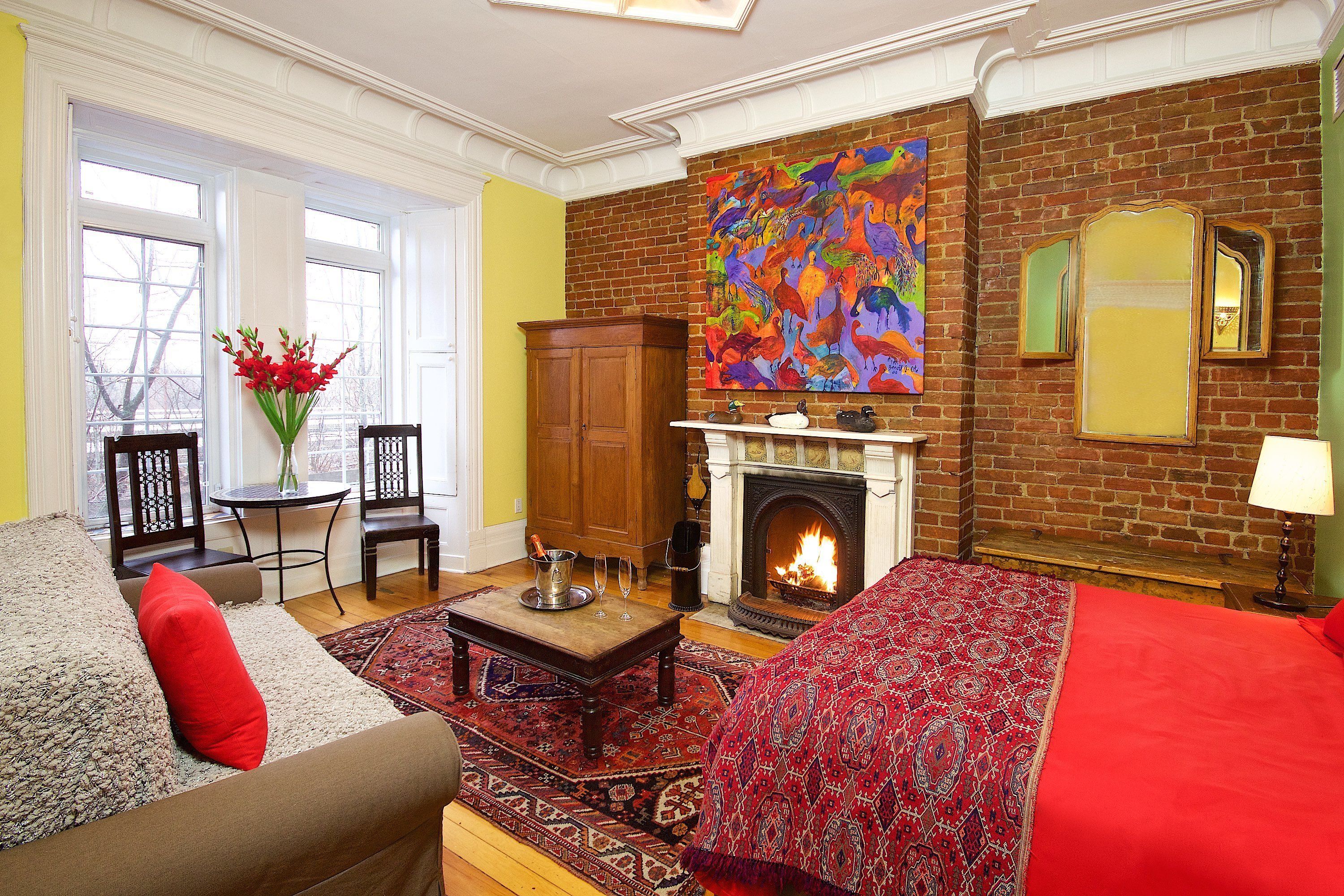 Una sala de estar acogedora con chimenea, un cuadro abstracto y colorido, y un plaid rojo con estampado en el sofá.
