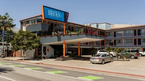Un hotel de varios pisos con un llamativo letrero de 'Becks Motor Lodge', estacionamiento exterior y una pasarela cubierta.