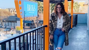 Una mujer caminando en un área exterior techada con un letrero que dice 'Becks Motor Lodge'.