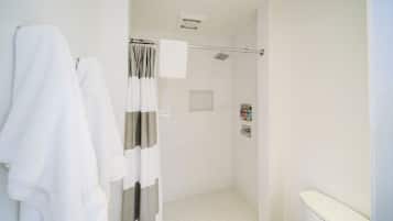 A modern bathroom with a shower, white tiles, a towel rack, and a toilet.