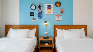A hotel room with two beds, a nightstand with a lamp, a framed picture, and a poster on the wall.
