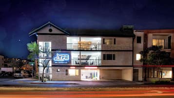 Un hotel de varios pisos con una entrada visible en la planta baja y un balcón en el segundo piso, e indicación de que es un YFE Inn Suites.