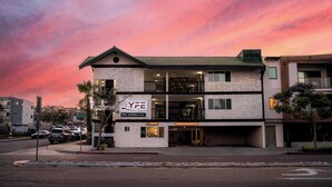 A hotel with a sign reading 'LYFE INN SUITES,' a two-story structure with a balcony on the second floor, and a parking lot in front.