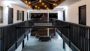 A multi-level interior with a staircase, black railings, and hanging lights.