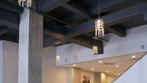 Un moderno hall de entrada con un sofá de cuero negro, taburetes metálicos y candelabros de cristal colgantes.