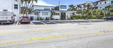 A hotel named "Castle by the Sea" with a parking lot, a white building, and palm trees.