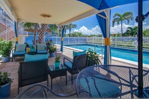 A covered outdoor area with a pool, seating, and potted plants. - Castle by the Sea (Lauderdale-by-the-Sea)