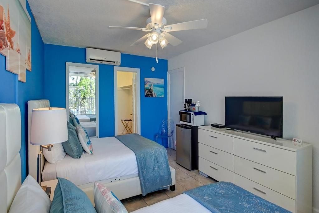 Habitación de hotel con dos camas, televisión, escritorio con microondas y aire acondicionado.
