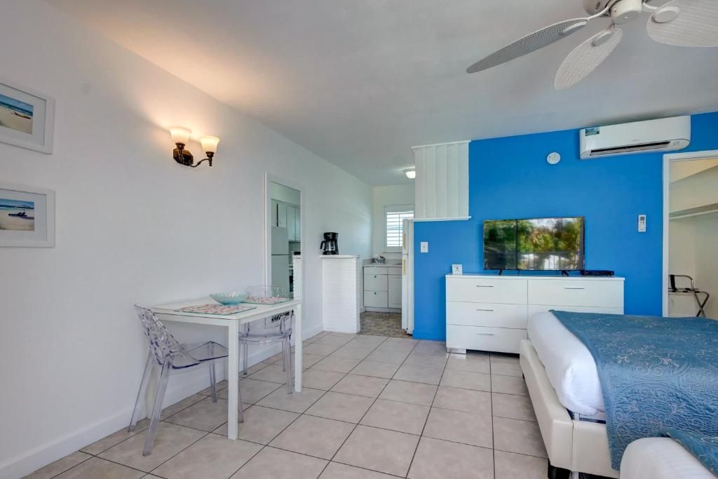 Une chambre à coucher comprenant un lit, un bureau, une chaise, un ventilateur de plafond et un téléviseur.