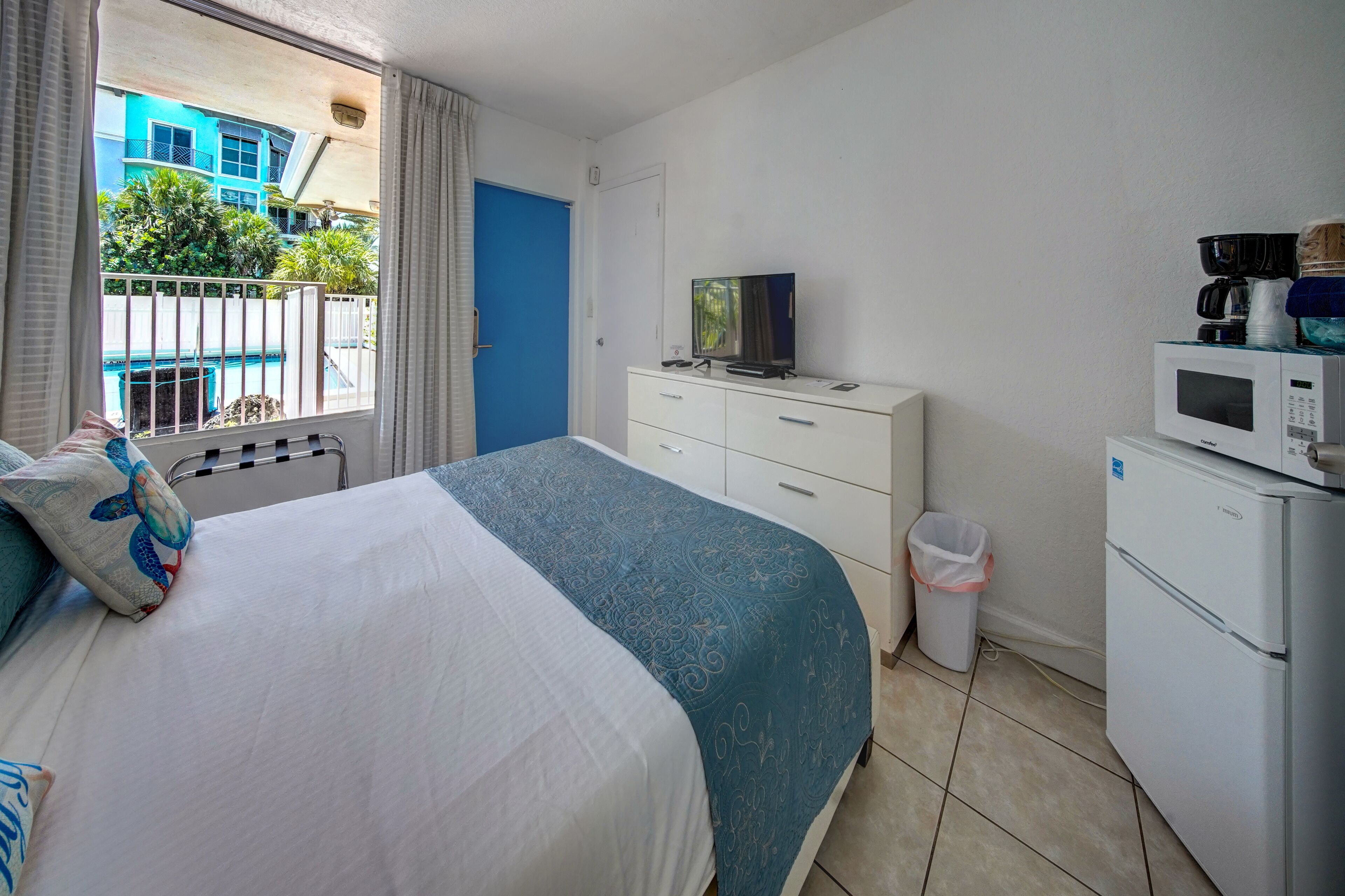A hotel room with a bed, a TV, a microwave, and a small refrigerator.