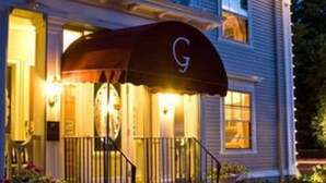 A two-story building with a covered entrance and a large 'G' sign.