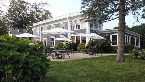 A large, two-story building with a symmetrical facade, multiple windows, and a well-maintained lawn.