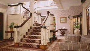 A grand staircase with a wooden handrail and patterned carpet, leading to an upper floor.