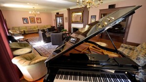 A grand piano in a living room with a sofa, a chandelier, and a fireplace.